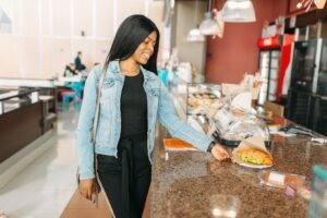 Black female traveler buying burger in airport