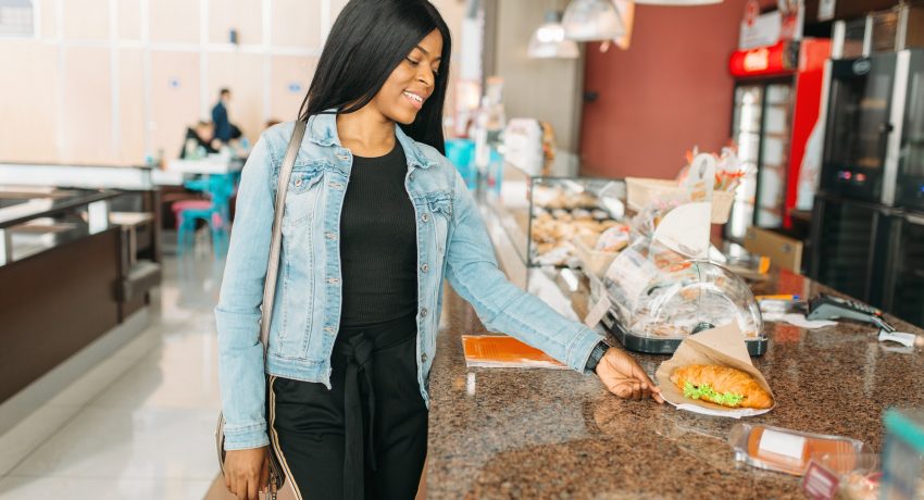 Black female traveler buying burger in airport