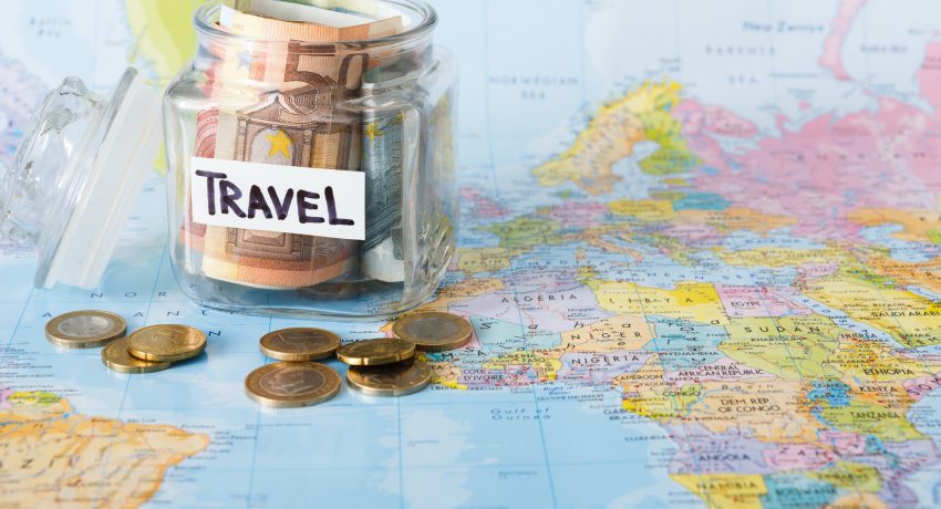 Travel budget concept. Money saved for vacation in glass jar on map background