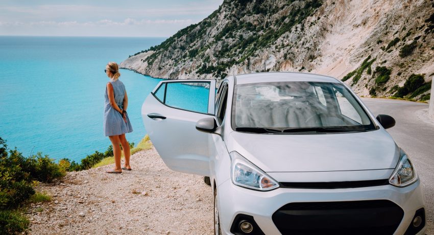 Women near rented car with open door enjoying Myrtos Beach. Travel vocation concept. Kefalonia